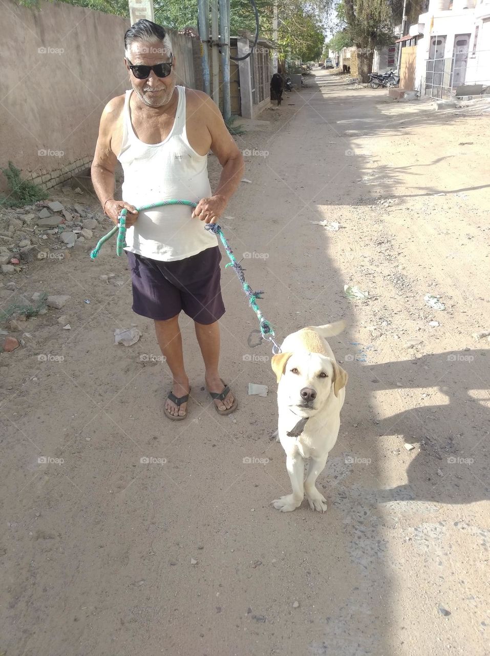 a man walking with his pet animal dog, white in colour looks very beautiful,it shows the bonding of both