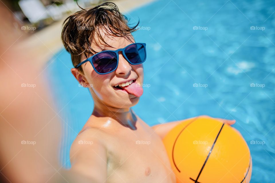 boy makes funny selfie in the pool