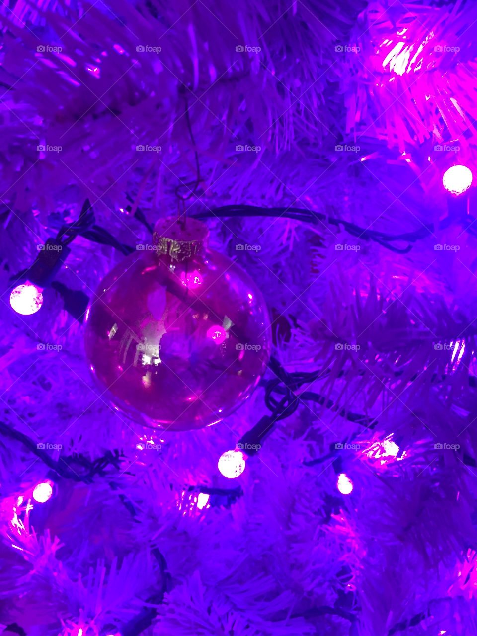 Purple Christmas ball hanging on a purple Christmas tree.