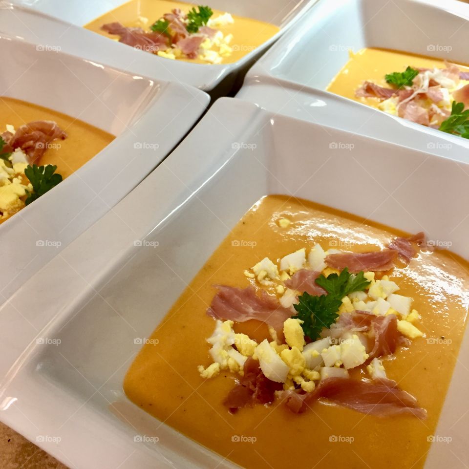Salmorejo - traditional Spanish soup with tomatoes, garlic, bread and Serano Ham and eggs toping in a rectangular white bowl
