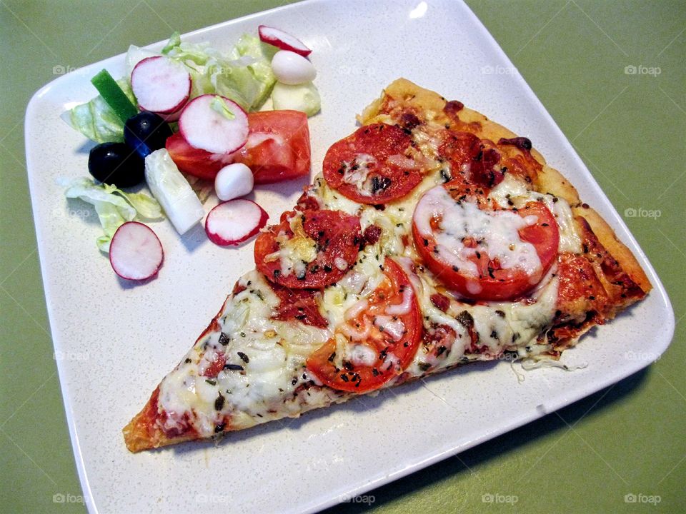 Sliced of pizza and tossed salad on plate