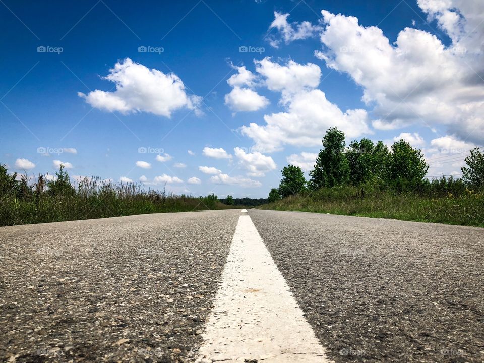Empty road on a sunny day with blue sky and fluffy clouds