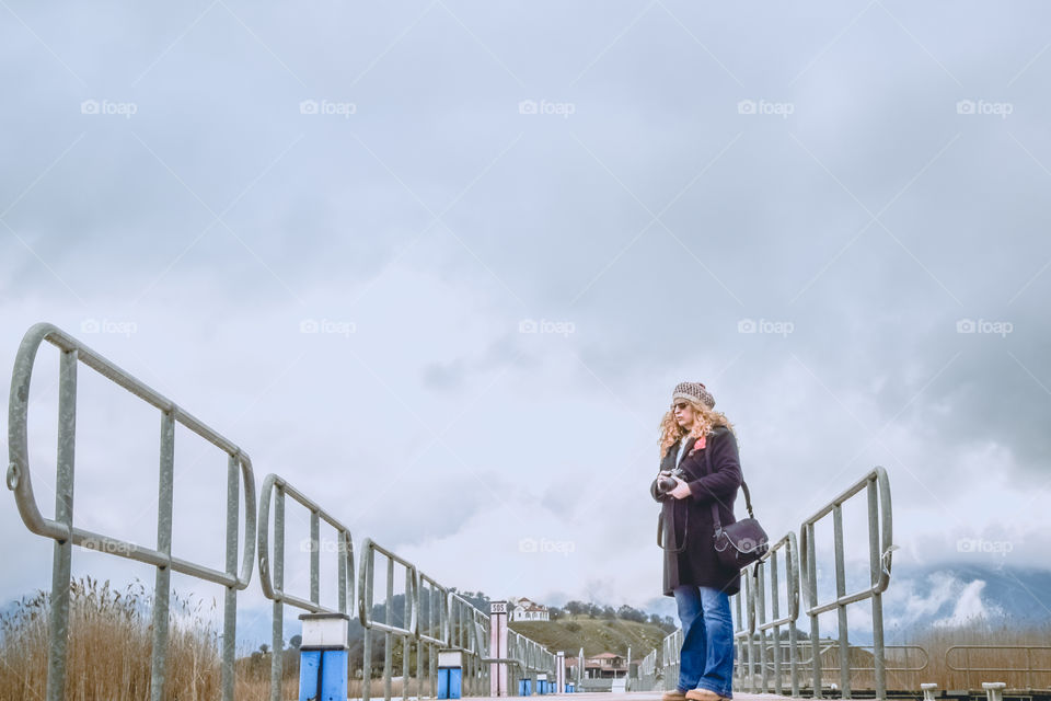 Beautiful Blonde Woman Photographer Wearing Sunglasses And Cap Holding Her Camera In Winter
