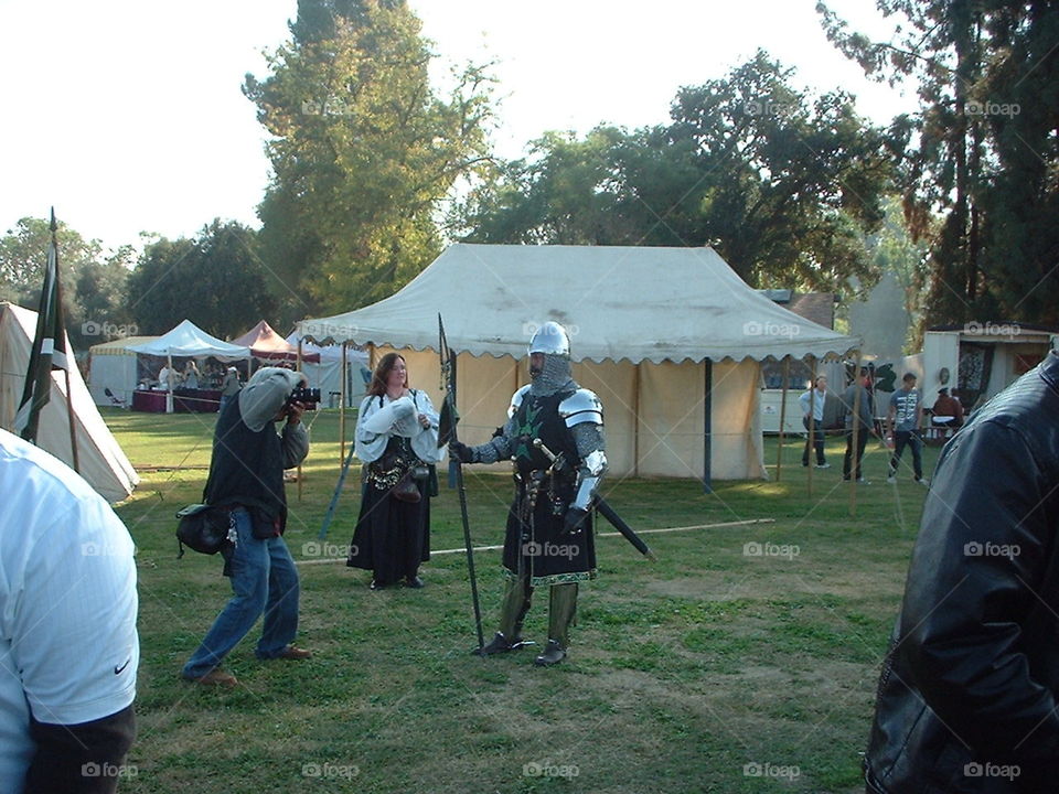 A brief photo shoot at the Renaissance Faire. The medieval knight is certainly given a celebrity treatment while his spouse looks on.