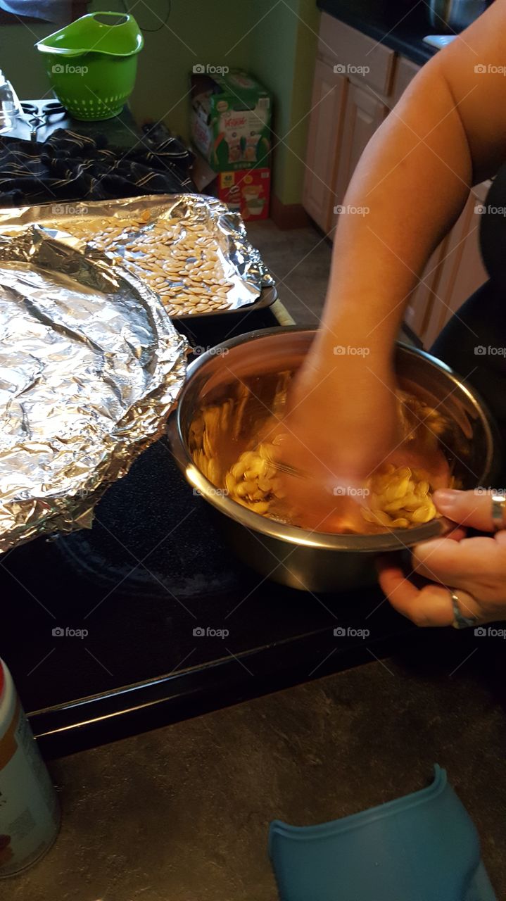 mixing seasonings in a bowl of pumpkin seeds