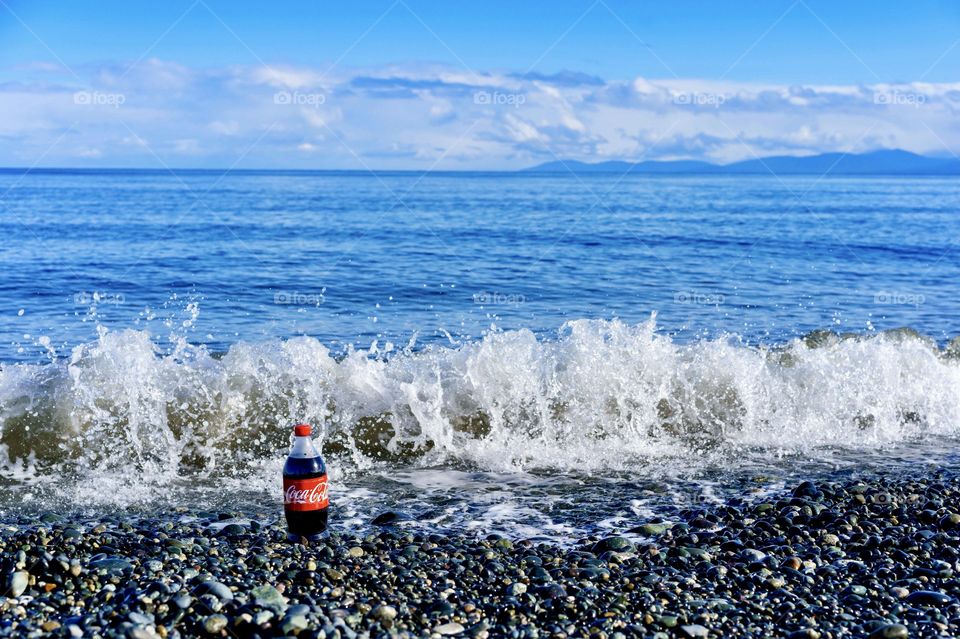 Ocean wave splashing on cola bottle 
