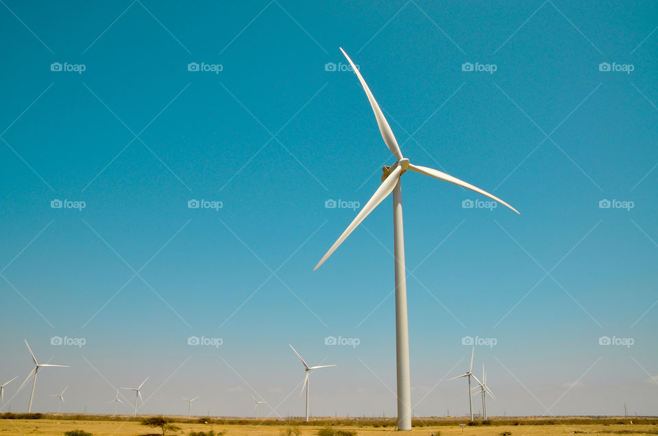 Windmill producing electric energy in desert landscape