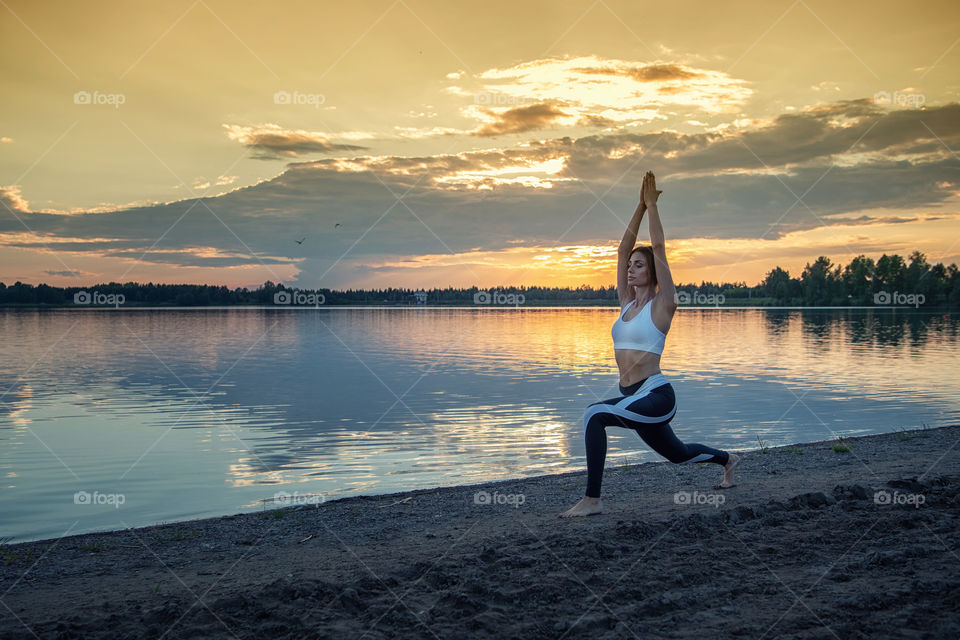 A girl is doing yoga on a lake shore
