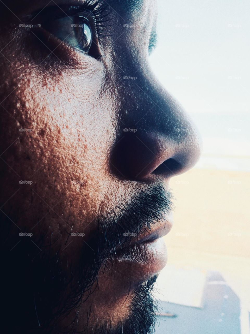 Man face close up, looking to the horizon while the natural light touch his face.