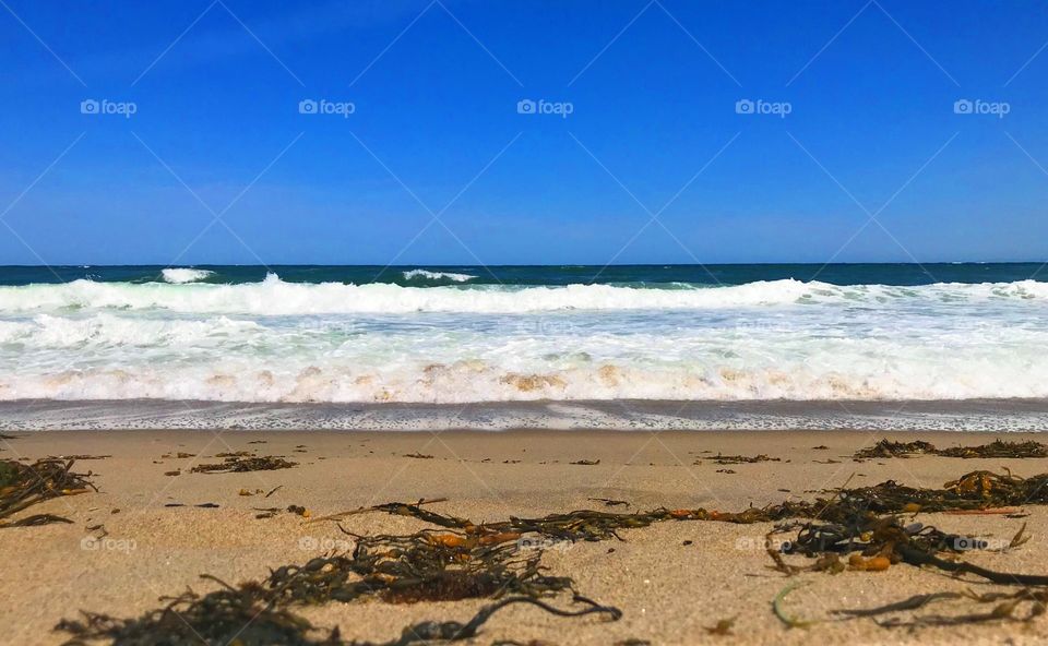 Vibrant photo of Hampton Beach on a warm summer day of the waves crashing ashore. 