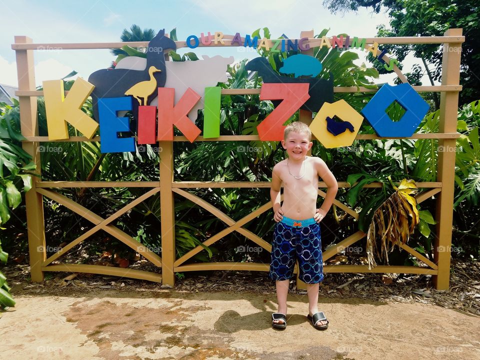 boy poses at entrance to keiki zoo