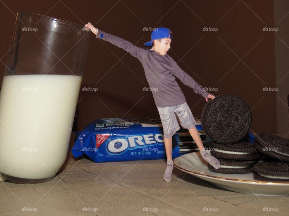 Boy hanging on milk glass and Oreo cookie