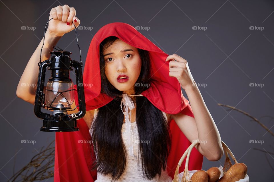 Girl lost in the woods holding bread and lamp