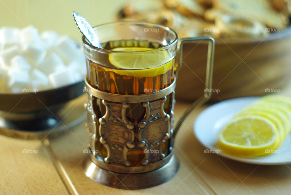 Tea in a glass in an old cup holder with drying and lemon