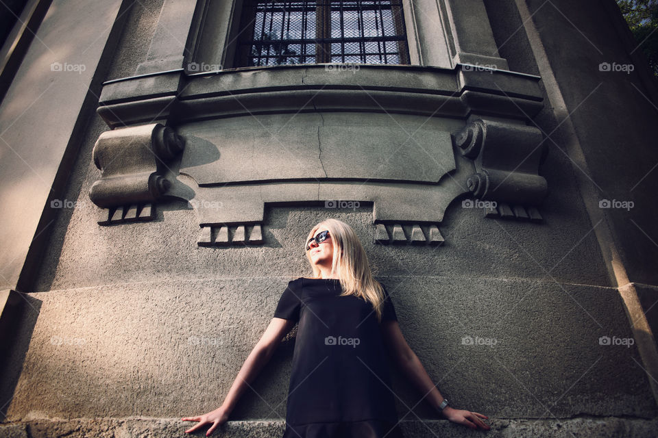 Blonde woman standing under the window