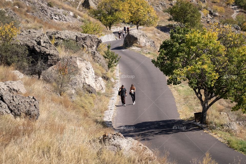 Tourists are walking along beautiful road to The famous cave town of Georgia, Vardzia cave monastery