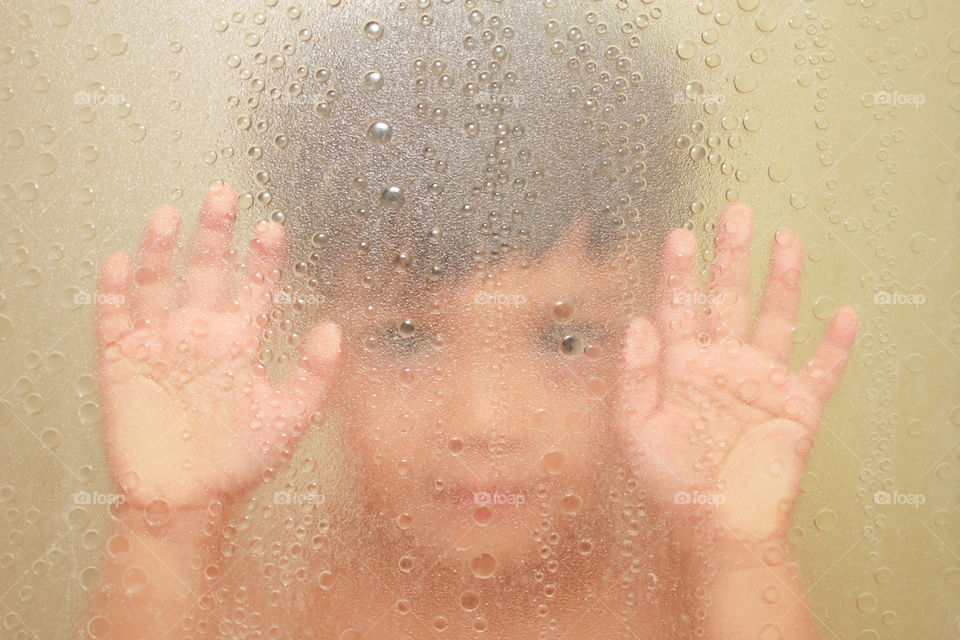 boy hand pressed on the bathtub glass.