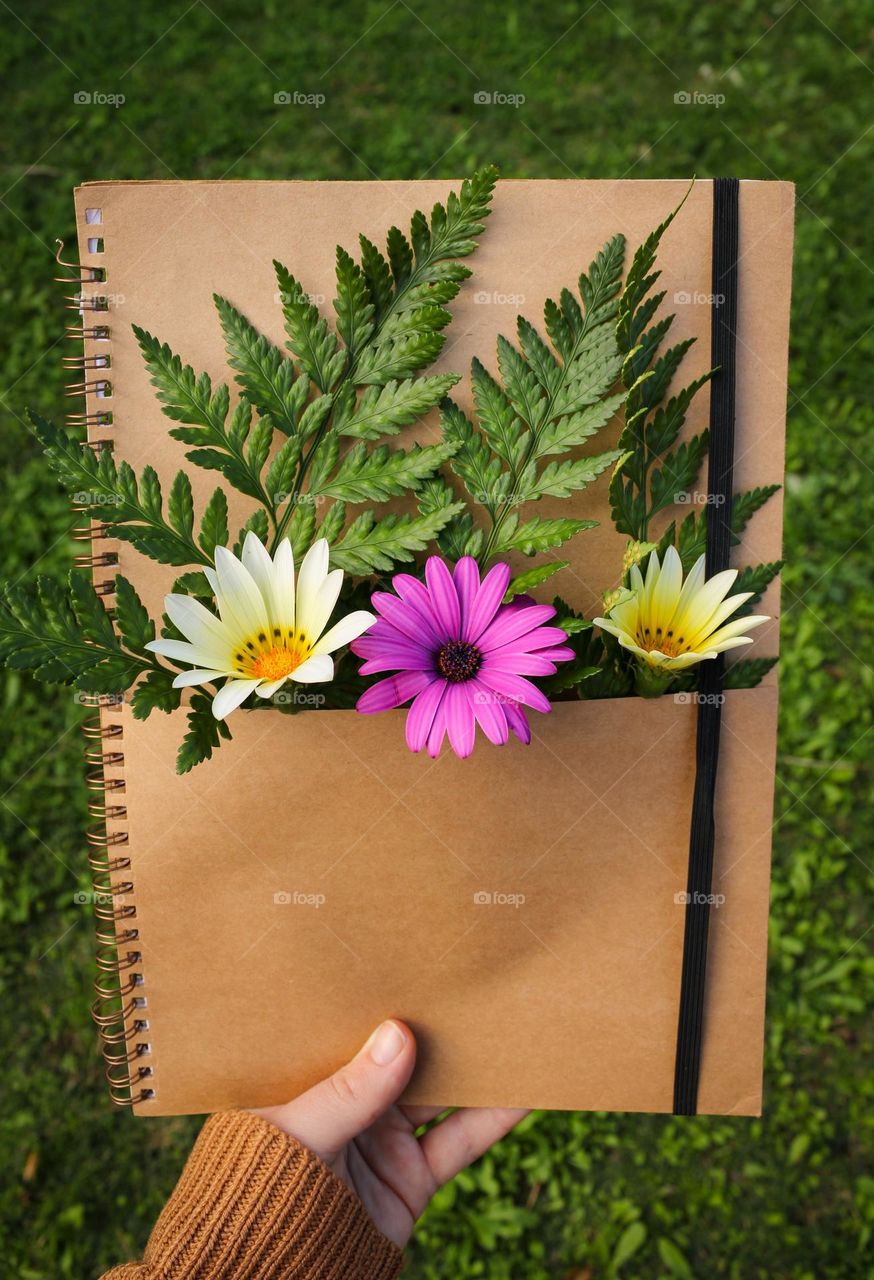 A hand holding a beautiful book with flowers