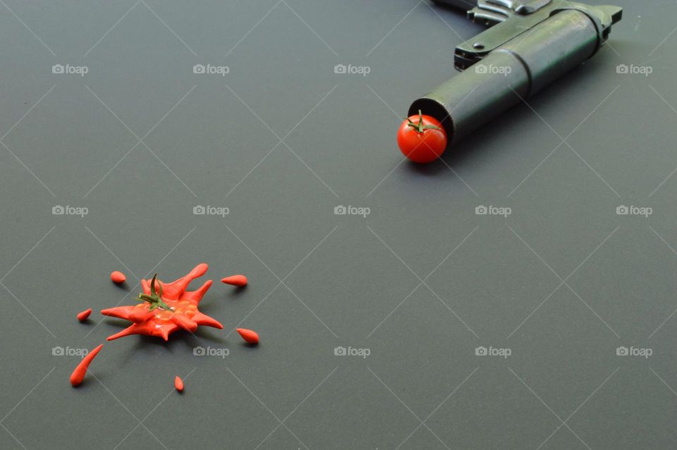 Firing with tomatoes from a pistol on a dark background smeared to smithereens tomato