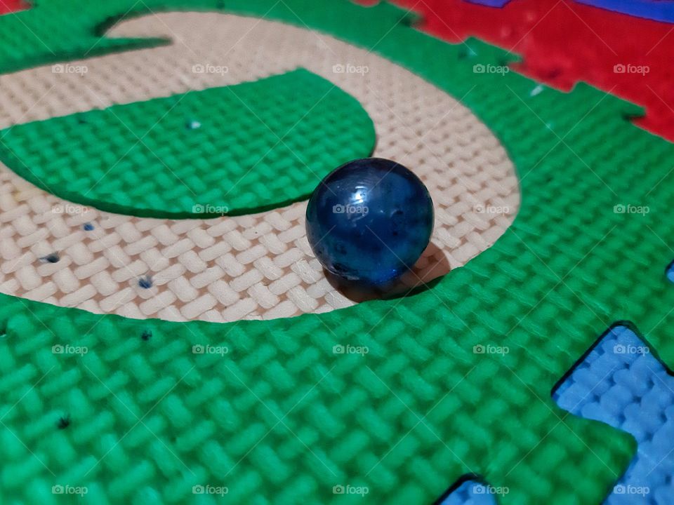 a blue small marble on the colorful matras.