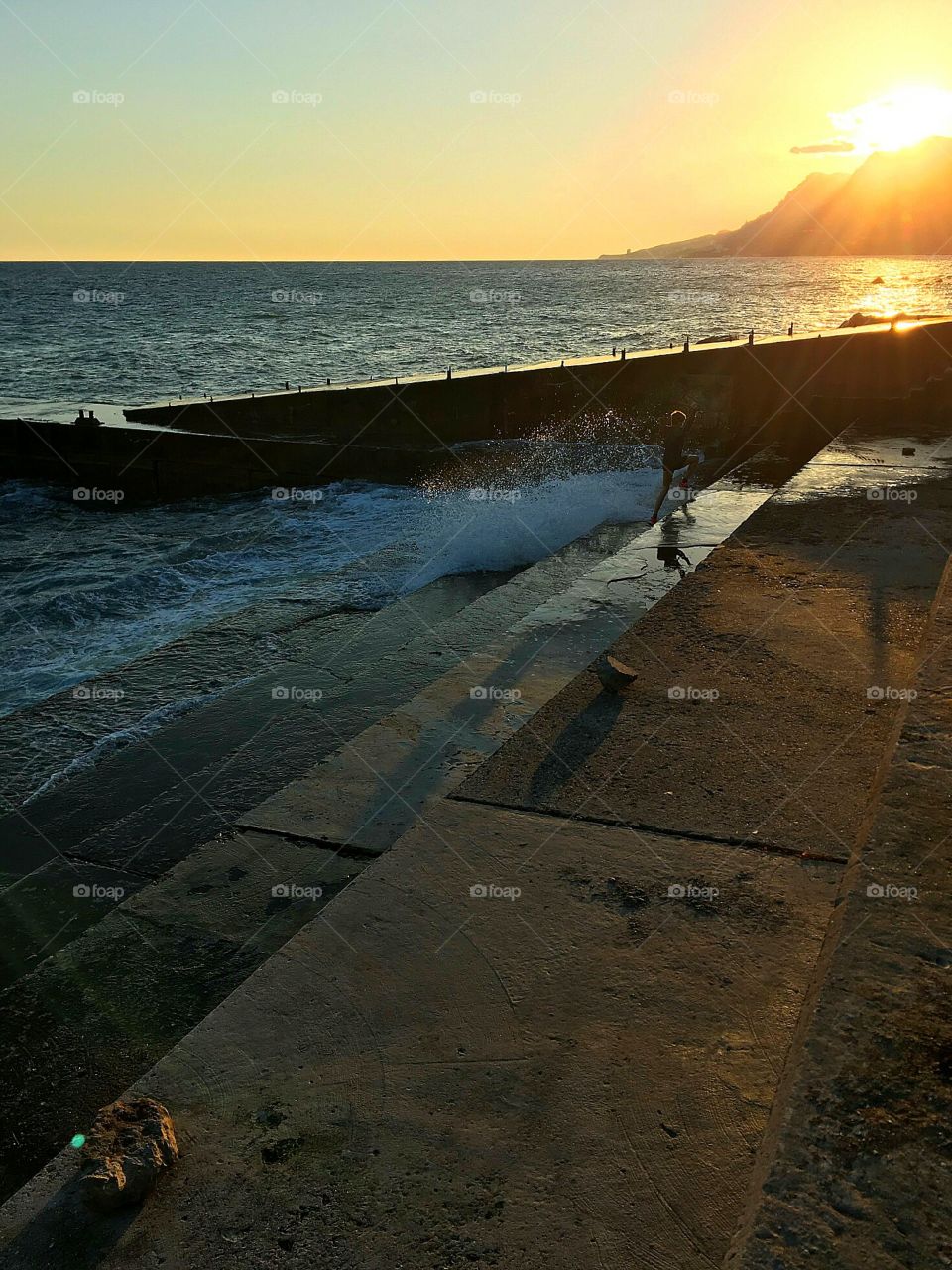 Boy , playing with waves at sunset.