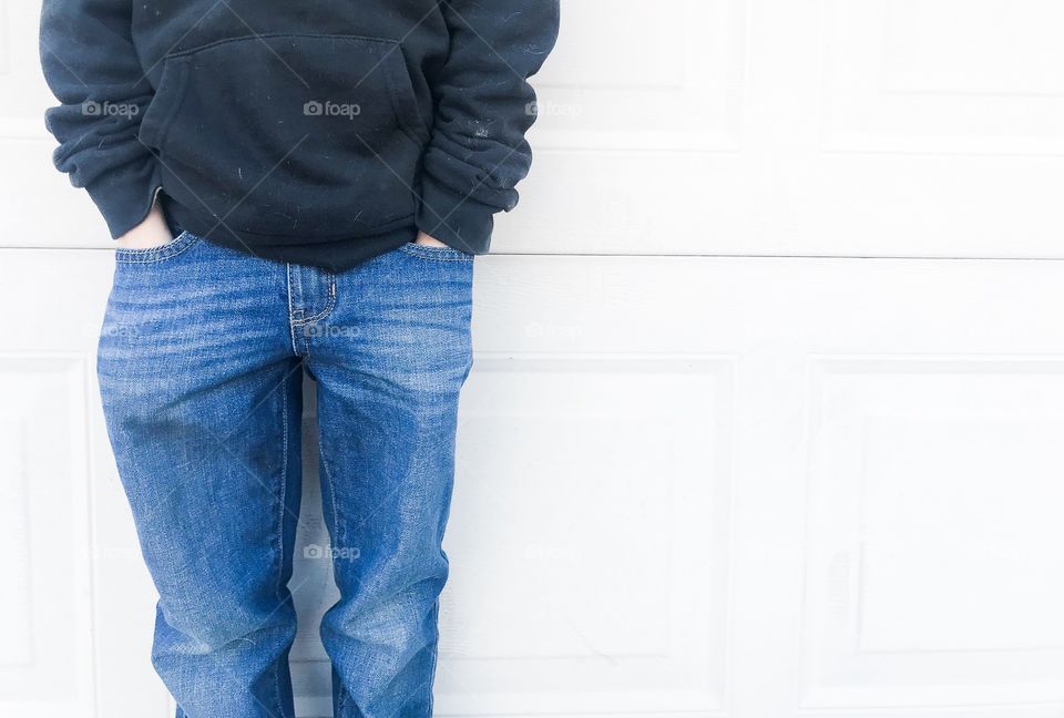 Boy standing with hands in his blue jeans wearing a black sweater 