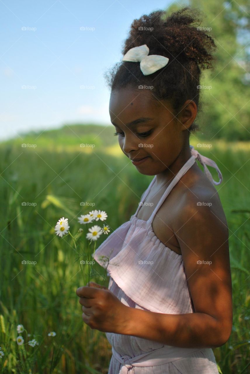 Girl of mixed race walking outdoors in barley fields during summertime