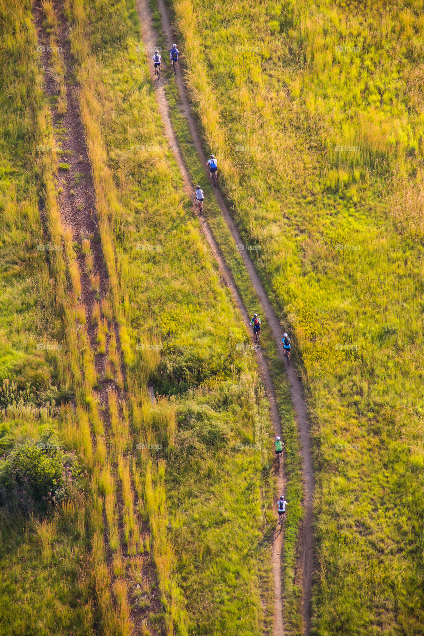 Cyclists in motion on gravel road bird's eye view from above just after sunrise