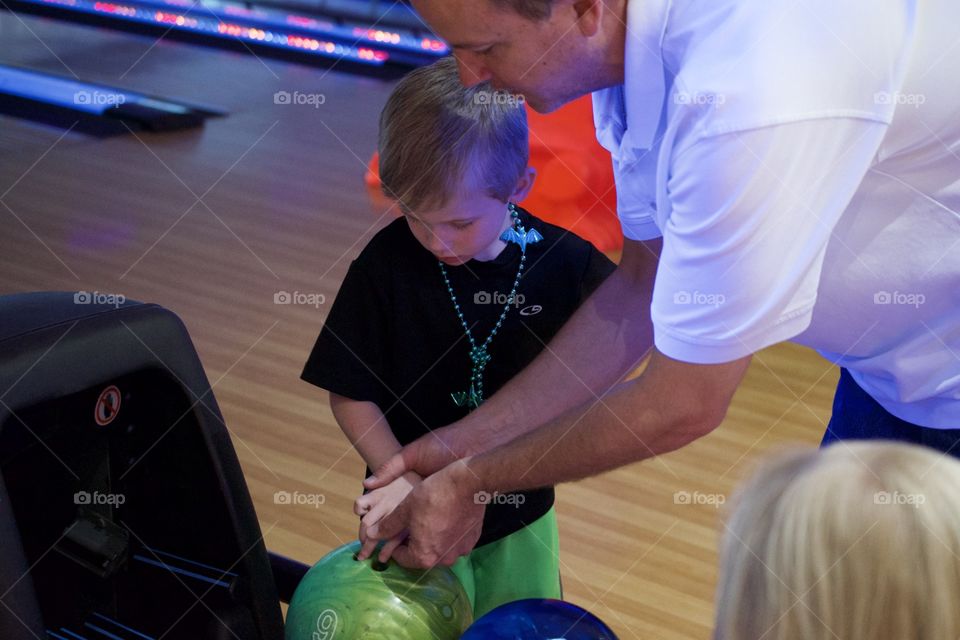 Father teaching son to bowling 