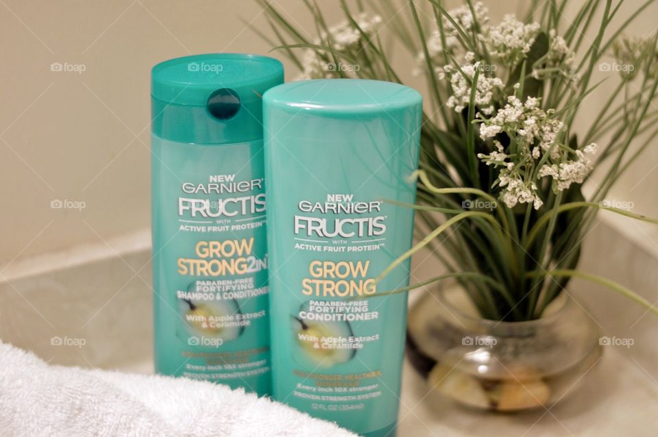 Garnier shampoo and conditioner on a bathroom countertop with a white towel in a plant in the background