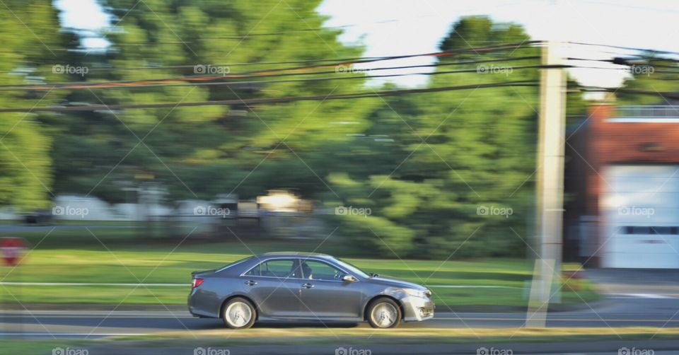 Driving through. Panning shot of a speeding car in the evening. 