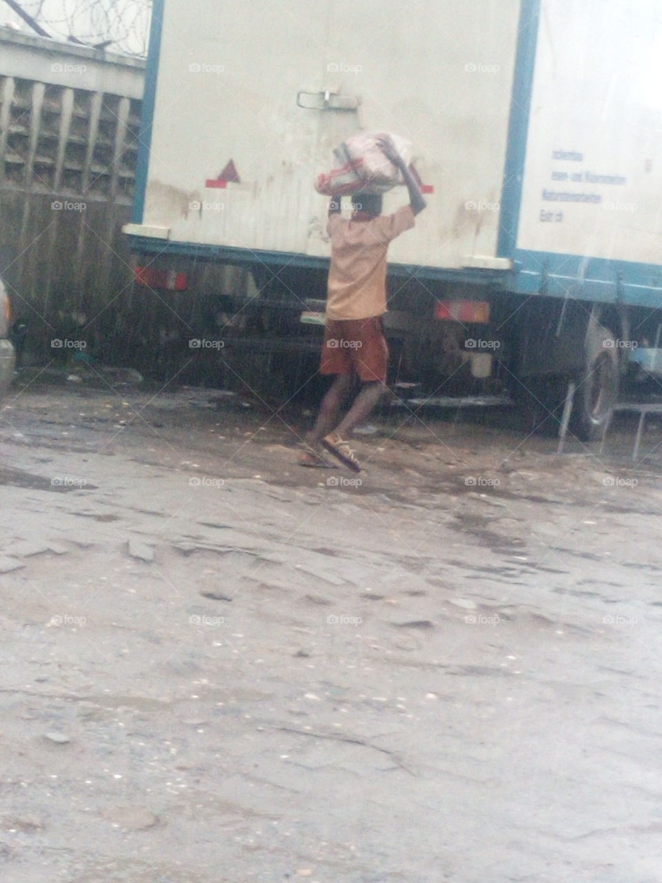 a boy carrying a load in the rain