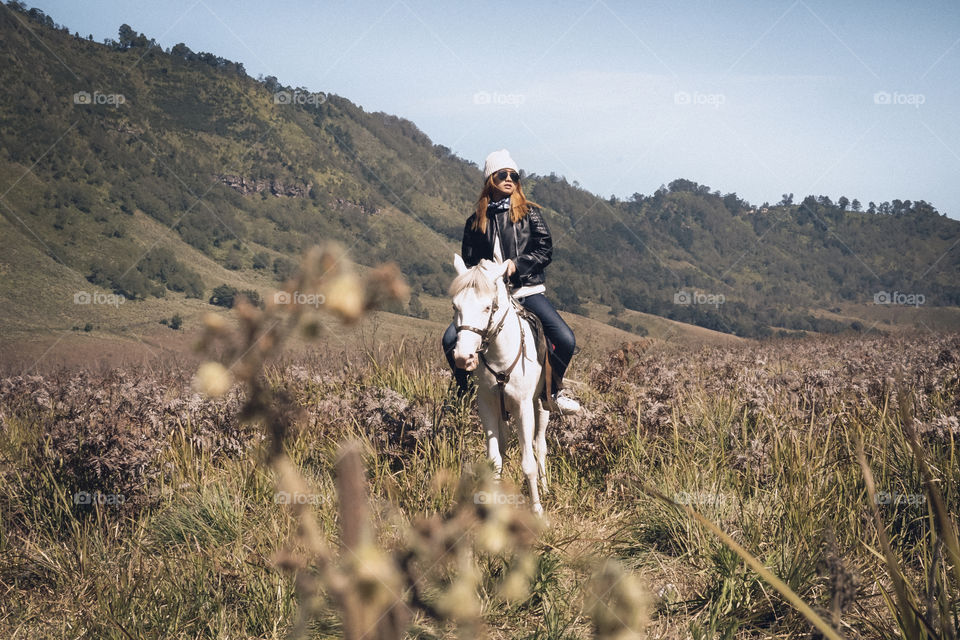 Young woman riding horse near mountain