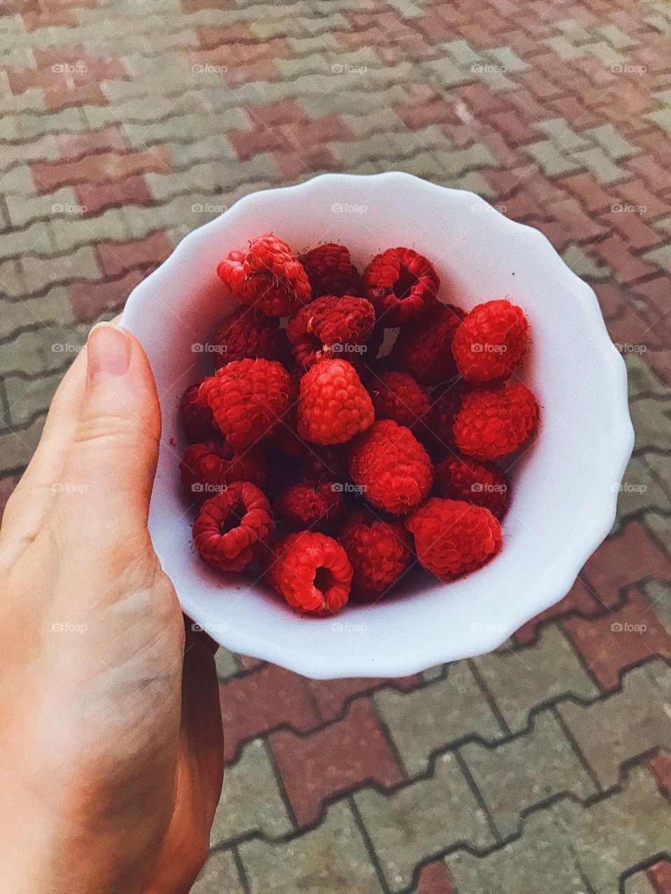 Fresh summer raspberry in the bowl in hand 