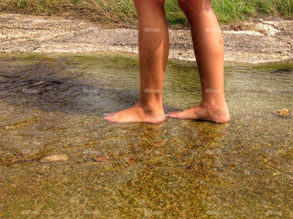 Summer day. Girl walking in a small stream of water