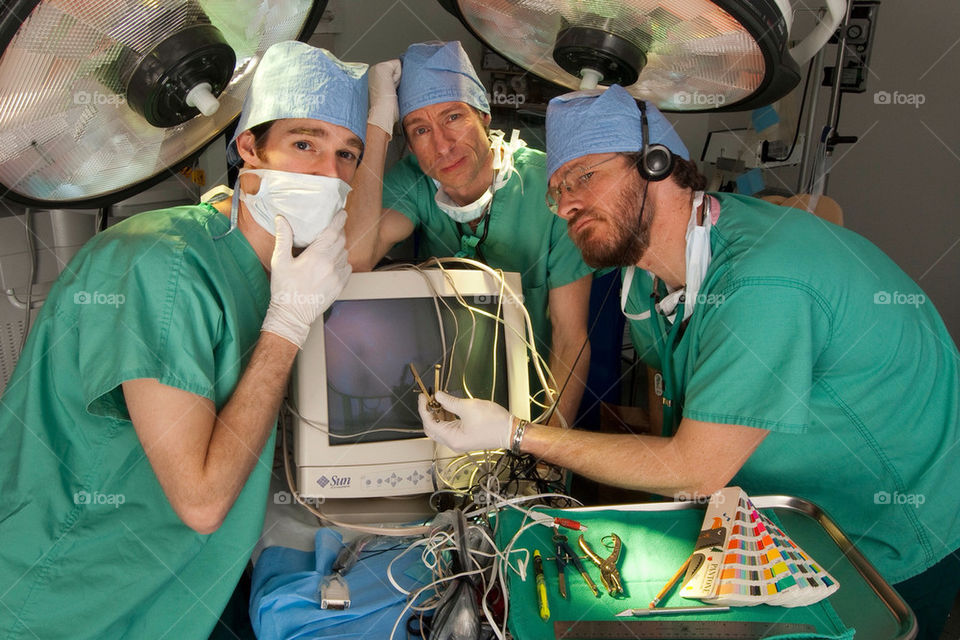 Three doctors operate on a computer in an emergency room