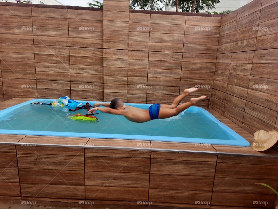 child jumping in the pool having fun in summer