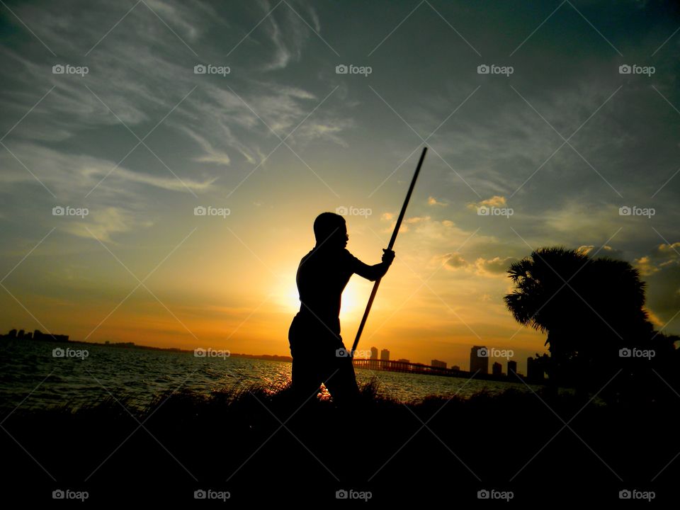 Silhouette of a man holding stick