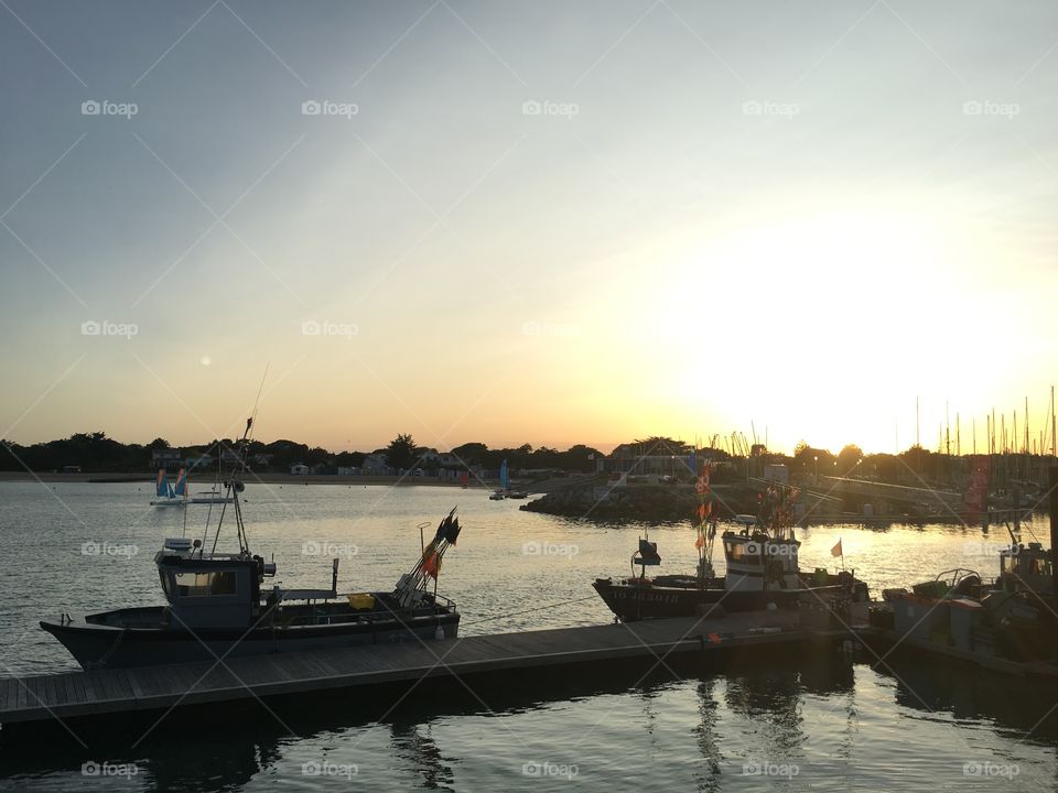 Fishingboat on sea with sunset behind Harbor 