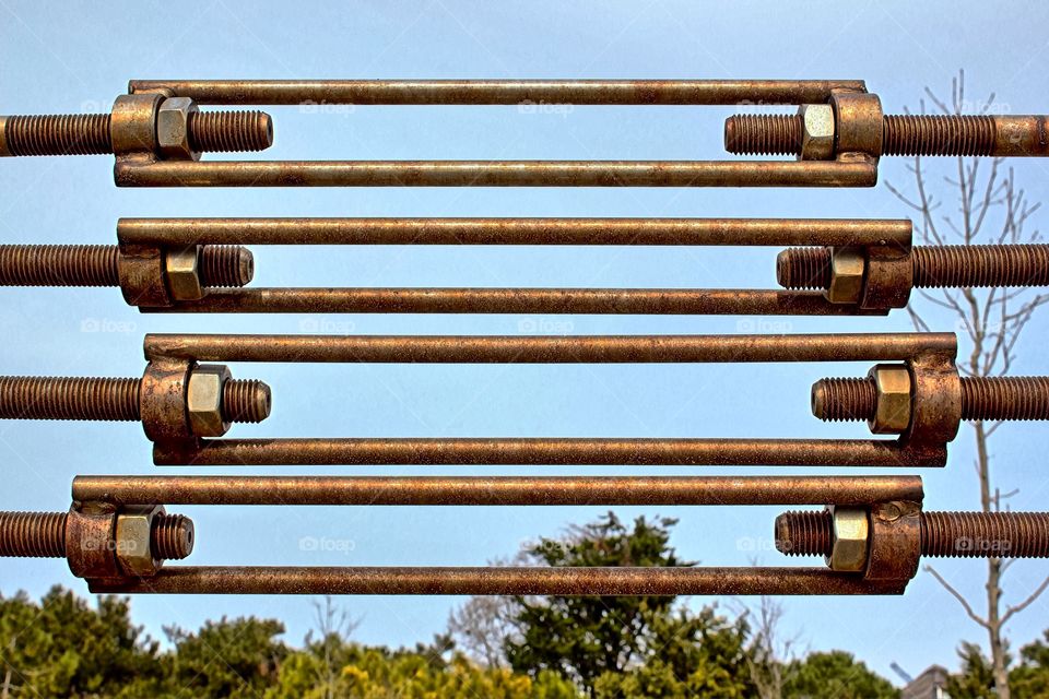 The seaside rusty fence, bolts and nuts, sky, trees