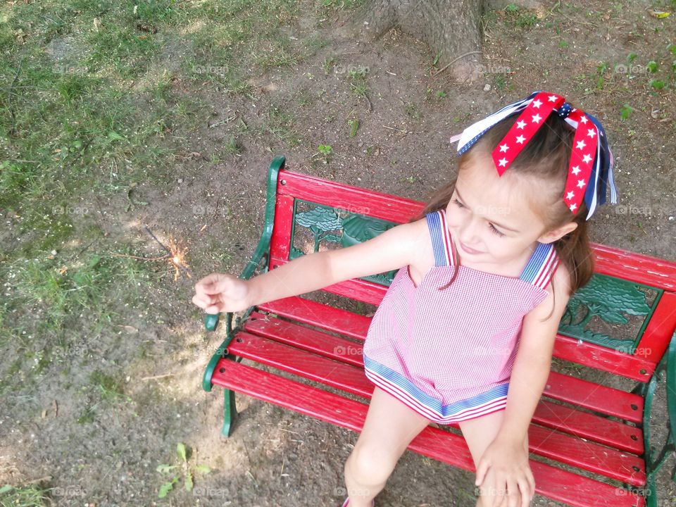 Little Fircrackere. Littler girl dressed in red, white and blue playing with a sparkler. 