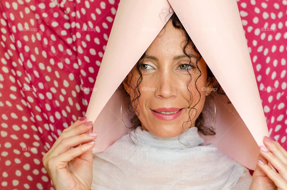 Portrait of a woman brunette on pink background