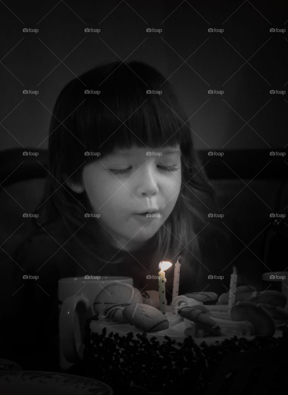 A little girl blows out the candles on the cake