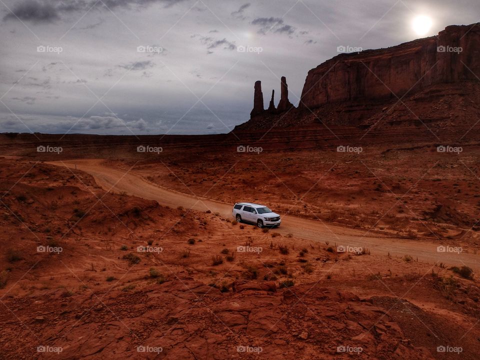 Malik drive. 
This is Monument Valley in Utah. Magnificent spot. You may have so many good shots out there. I climbed on a hill and noticed that car driving. This red color of la d and a white car are contrasting pretty well. 
