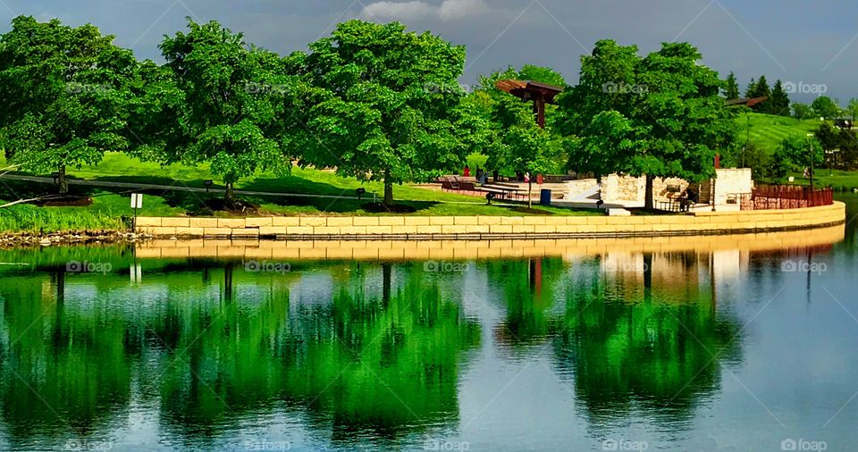 Storm clouds behind trees reflecting in the pond of a park—taken in Munster, Indiana 