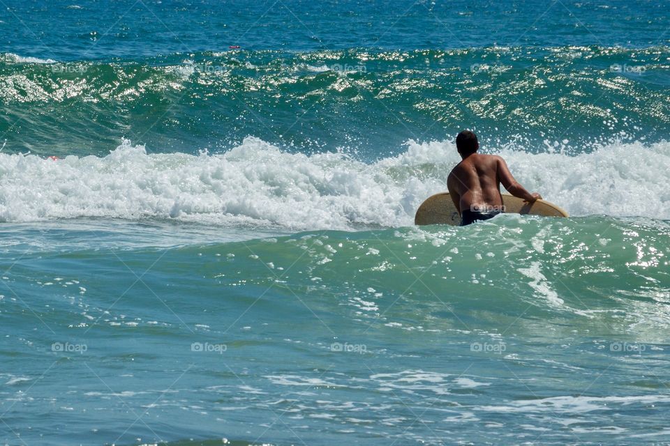 Back view of man with surfboard at the sea