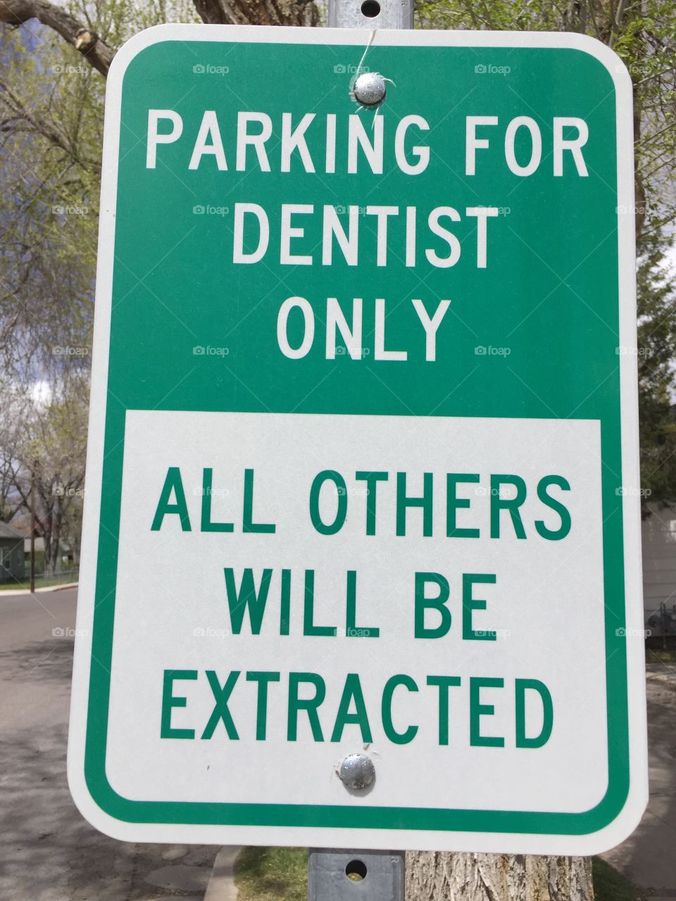 Funny sign. Parking for dentist only, all others will be extracted. Green and white.
