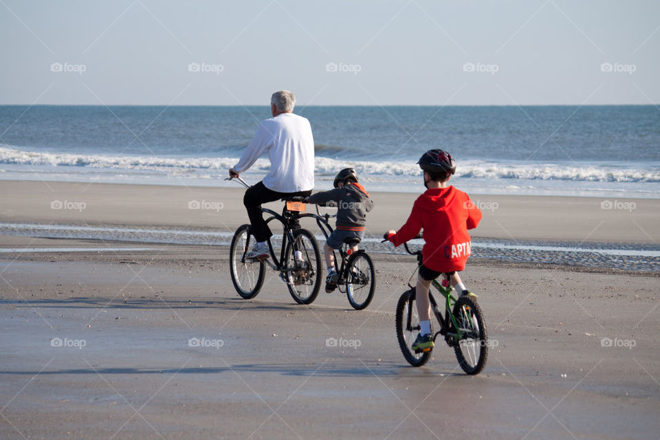 Father And Sons Riding Bikes On The Beach Father And Sons Riding Bikes On The Beach