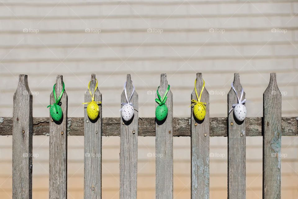 Colored eggs hanging on the wooden fence 