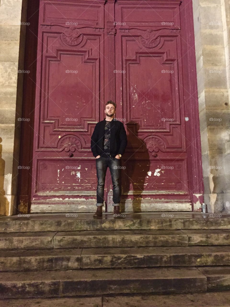 Young man standing near old door